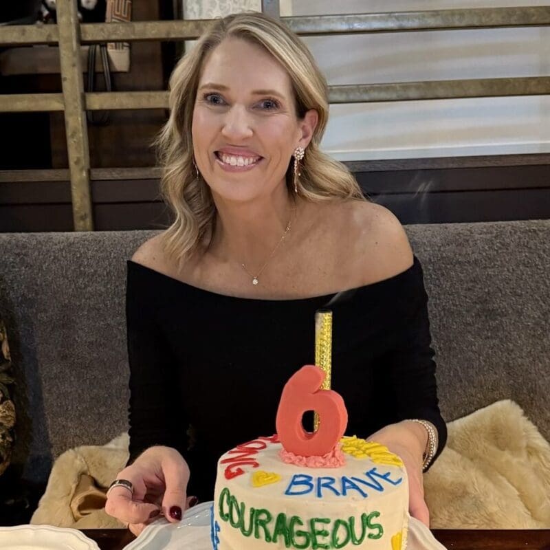 Leah Phillips was diagnosed with stage IV EGFR NSCLC in 2019 at 43 years old. She is celebrating her 6 years of survival with a cake in front of her while she is smiling.