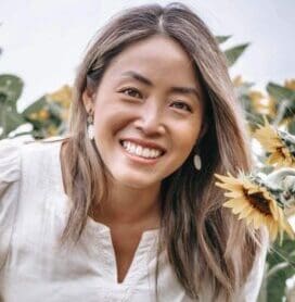 Mai, a lung cancer patient from Canada, smiles with sunflowers.