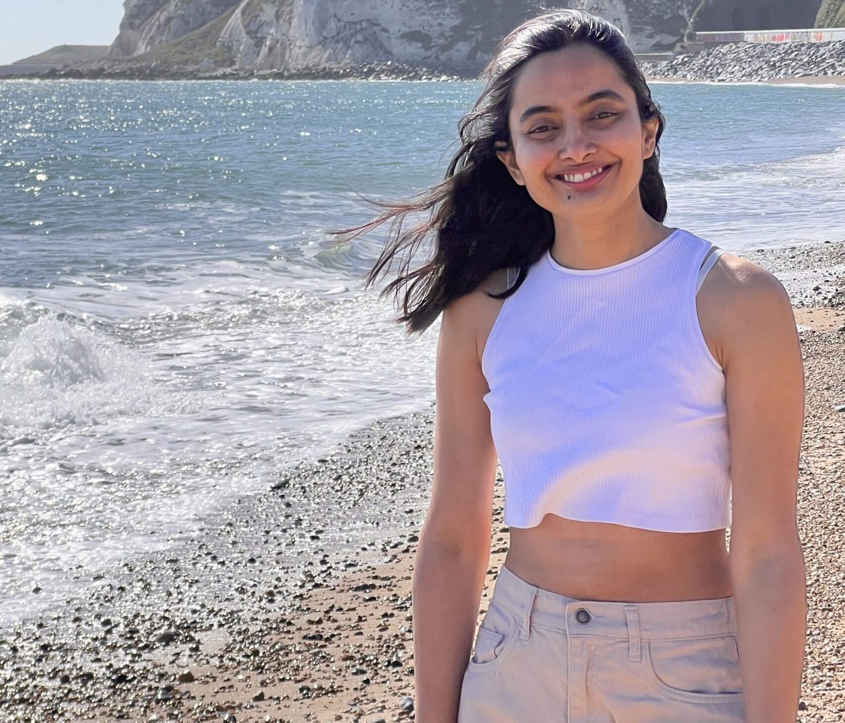 Rasika, a young woman from India with lung cancer, smiles on a beach.