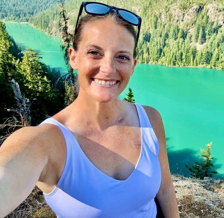 Faces of YLCI Kelsey Dellino, diagnosed at 34 years old with EGFR lung cancer, smiles while on a hike in the mountains