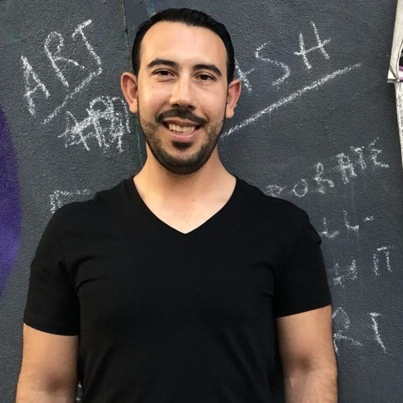 Pedro, a patient with lung cancer from California, smiles in front of a chalk board.