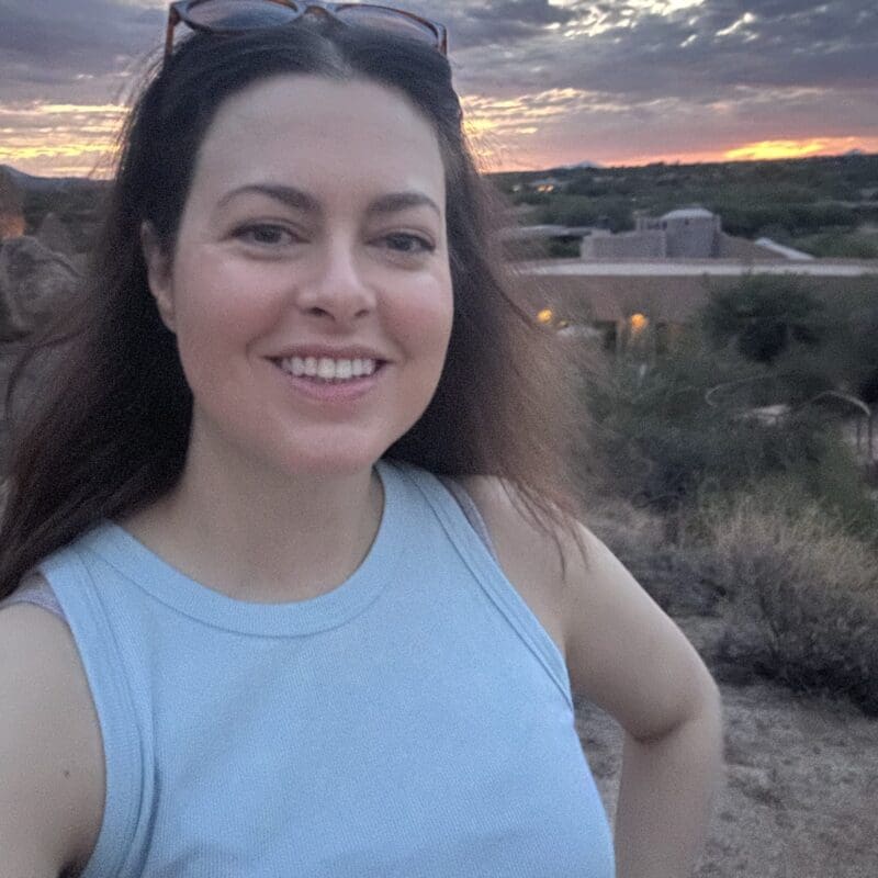 Stephanie, a young lung cancer patient with ALK + mutation, smiling with a sunset in the backdrop.