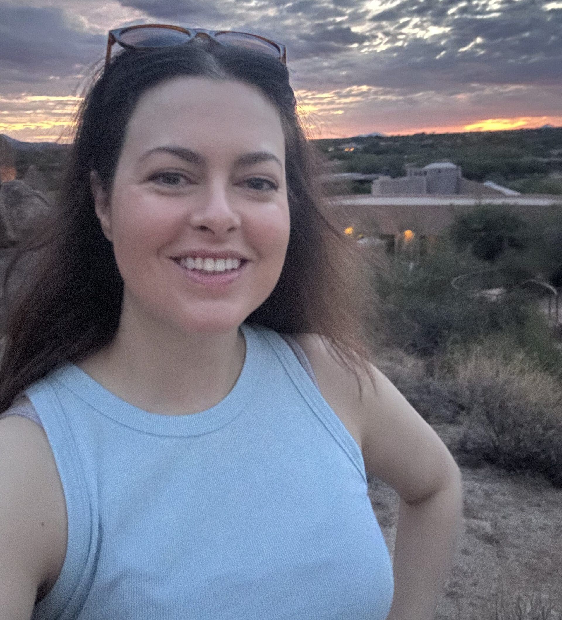 Stephanie, a young lung cancer patient with ALK + mutation, smiling with a sunset in the backdrop.