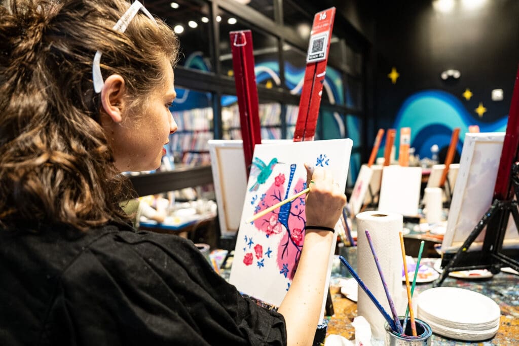 Lung cancer advocate Lauren Coye painting a hummingbird at a paint night event
