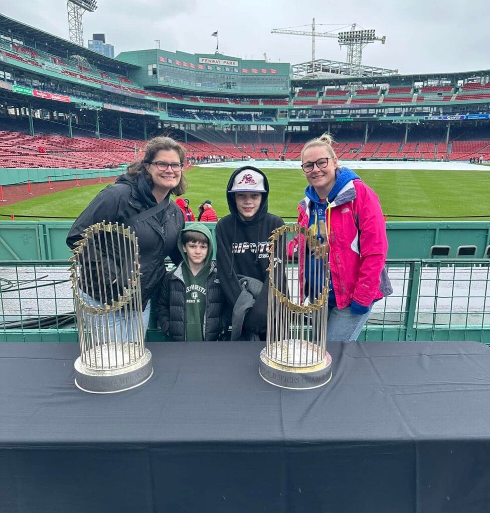 Theresa Woodbury with her family behind two World Series trophies at Fenway Park in Boston.