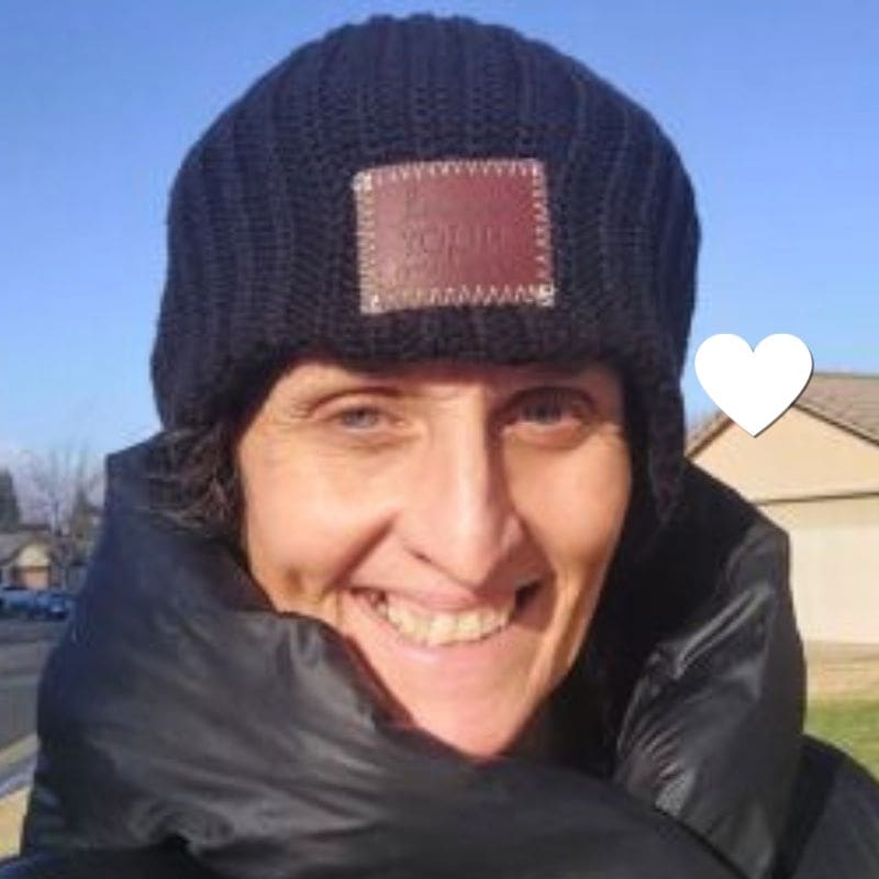 Piper, a young patient with lung cancer, smiles outdoors in a winter coat and beanie.
