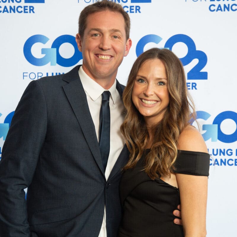 Emily, a long term stage 4 lung cancer survivor, smiles with her husband at a go2 for lung cancer gala
