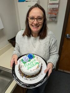 Luciana, a woman from Brazil diagnosed with lung cancer at 50, smiles holding a cake.