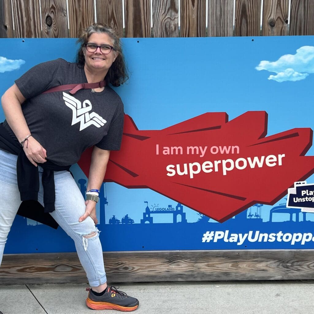 Theresa standing in front of an I am my own superpower mural