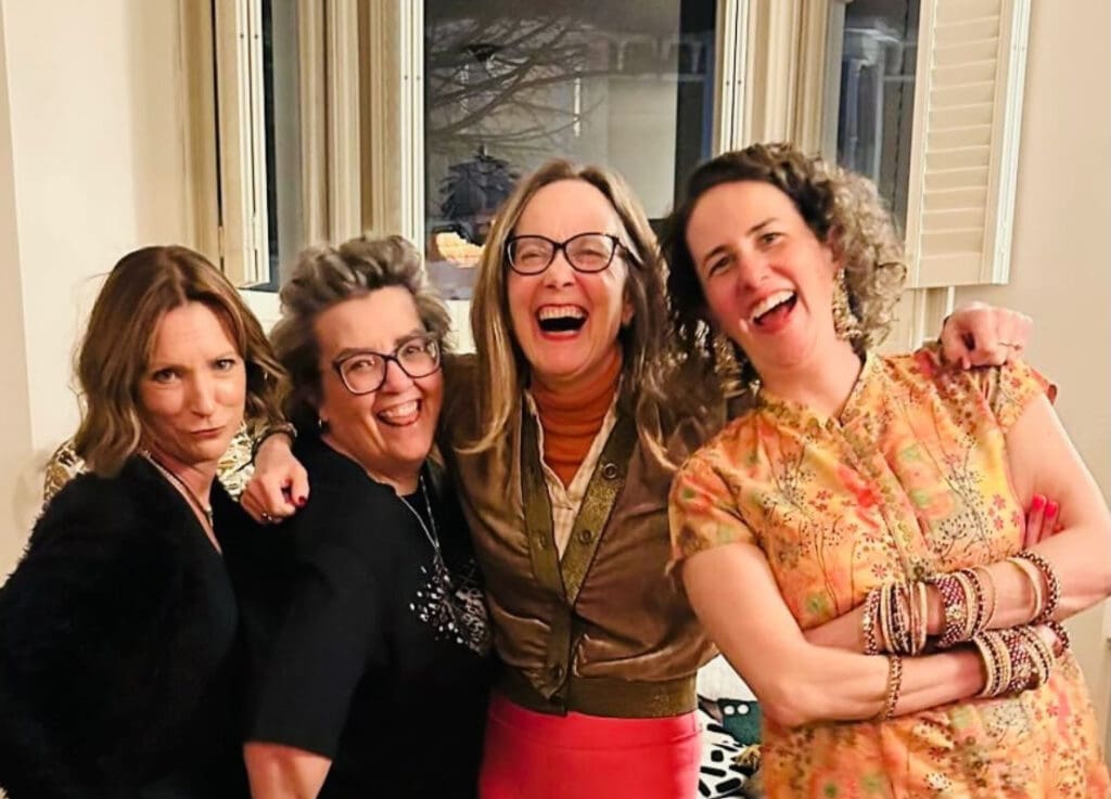Four UK lung cancer patients laughing together indoors with their arms around each other