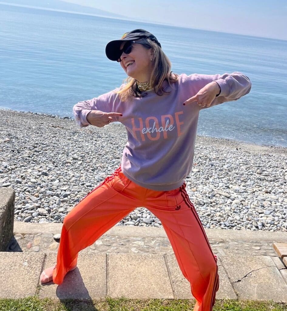 Mel Erwin, lung cancer patient, joyfully poses in YLCI merchandise - exhale hope sweater