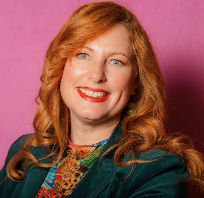 Young lung cancer patient, Iris, smiles in a headshot with a pink backdrop