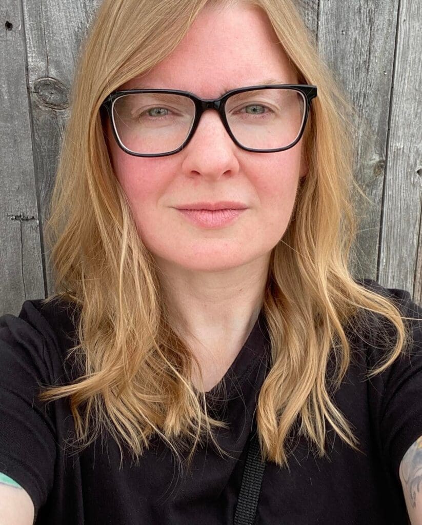 Caroline, a young lung cancer patient, wearing glasses and a black top