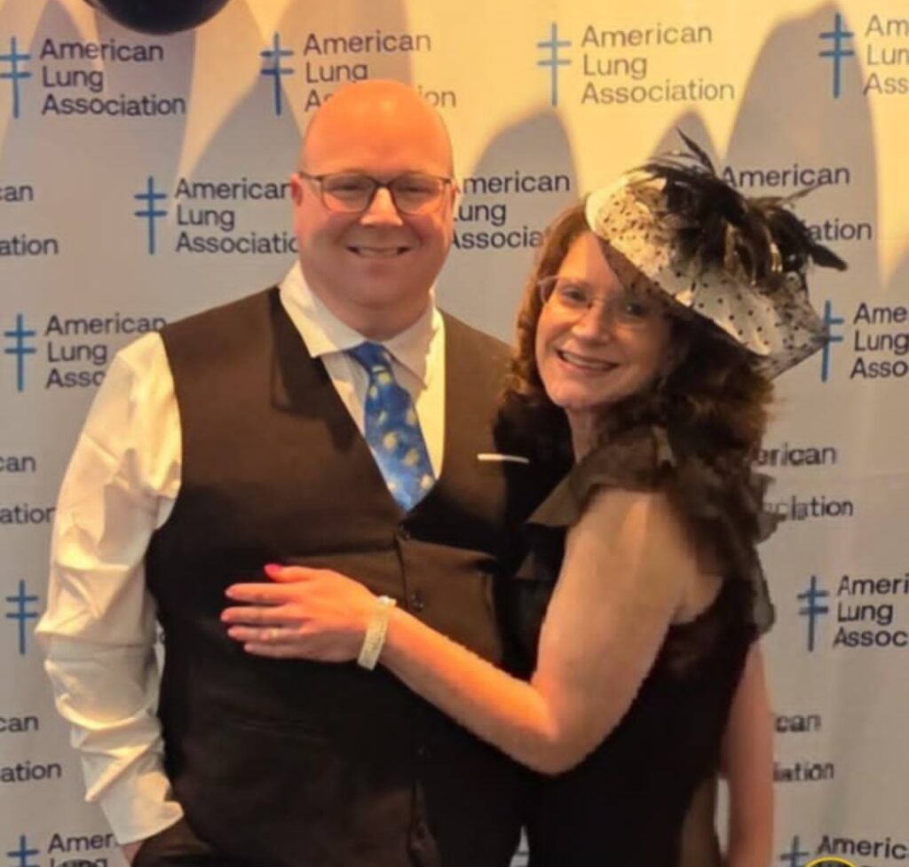 Young lung cancer patient and her husband smilng at an American Lung Association event wearing a hat